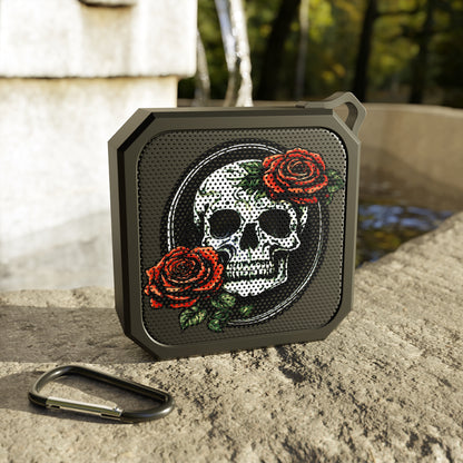 a Bluetooth skull and rose speaker displayed on a concrete ledge