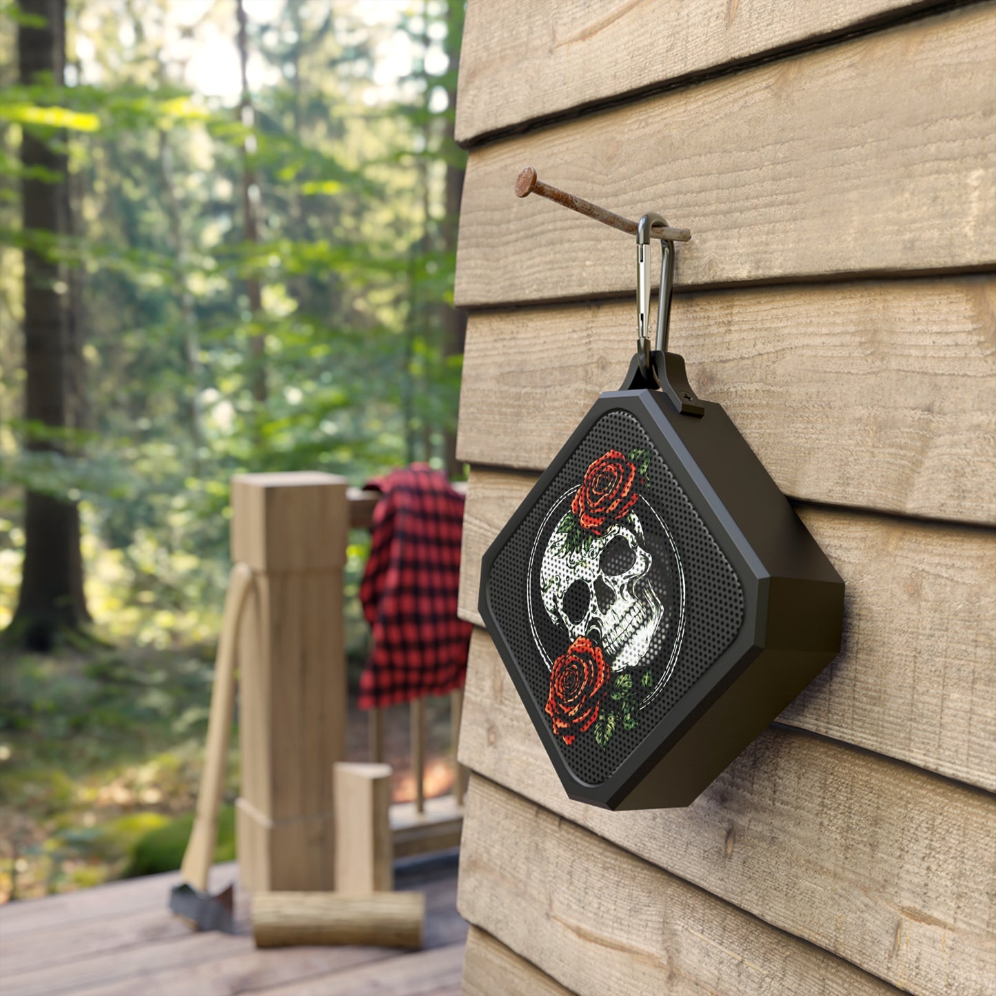 a skull and rose bluetooth speaker hanging from a nail on the side of a house